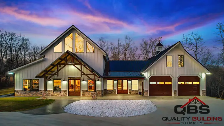 Barndominium at dusk with a timber-frame entry and lit windows