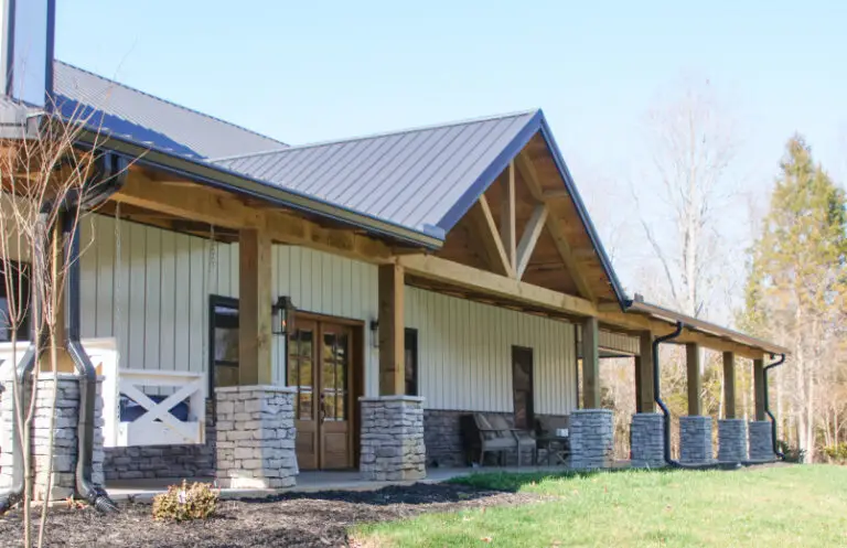 Barndominium with stone wainscot, a timber gable porch and a metal roof