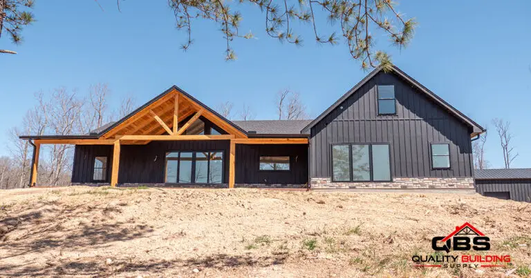 The Cypress Ridge barndominium with a timber gable entry and large windows