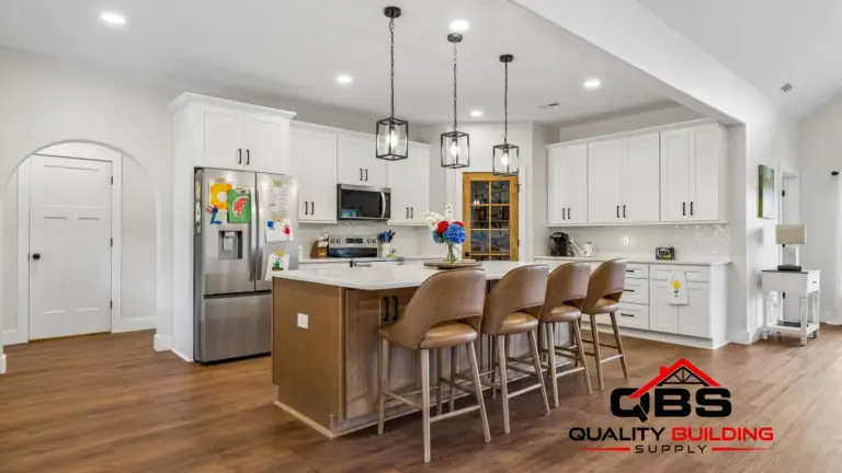 Kitchen with white cabinets, island seating and pendant lights in the Cypress Ridge barndominium