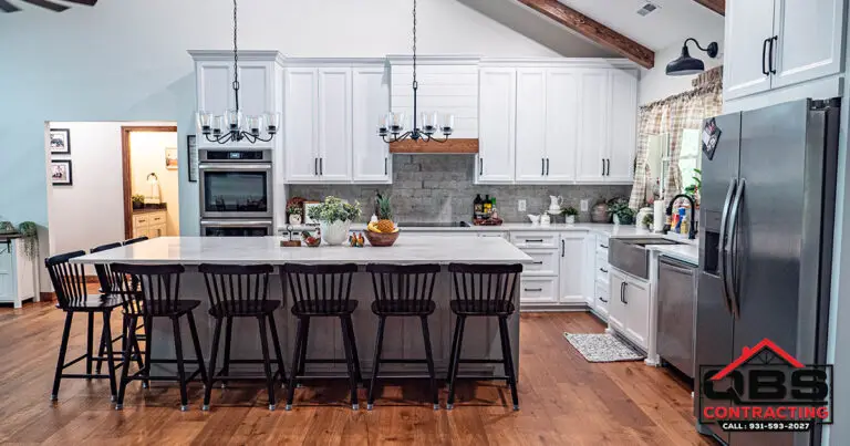 Kitchen with white cabinets and a black island in the White Oak barndominium
