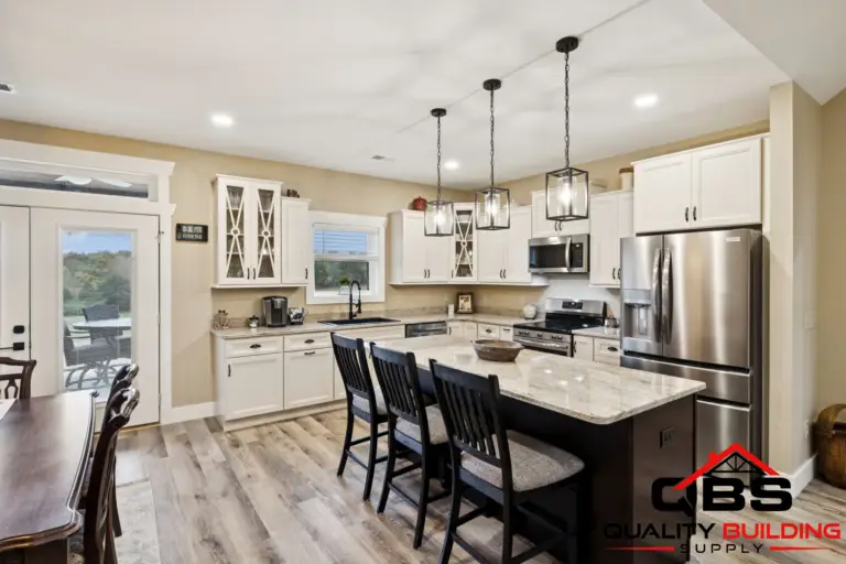 Kitchen with white cabinets, island seating and pendant lights in the Oak Grove barndominium